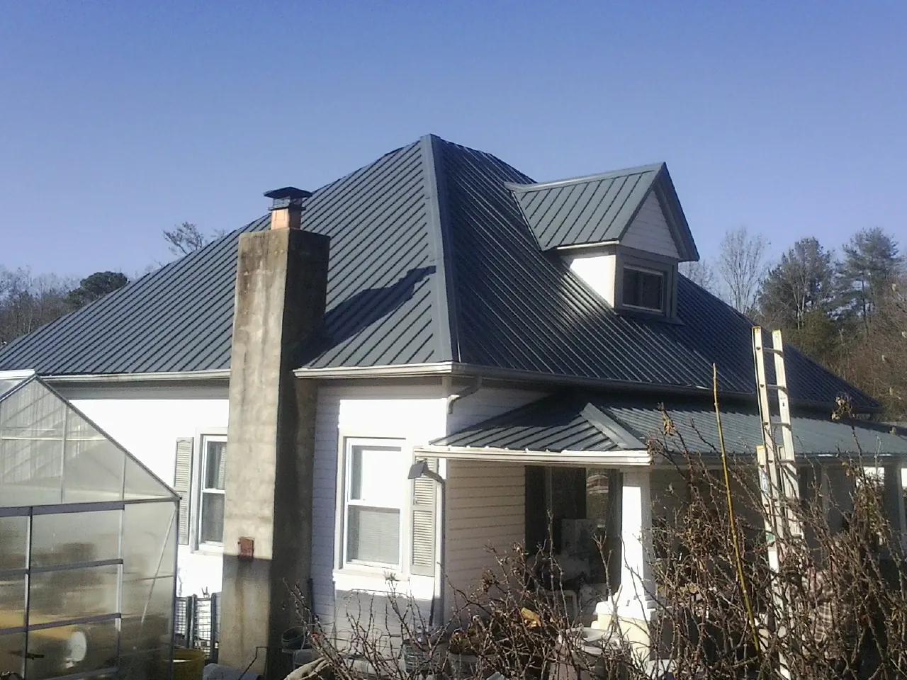 Dark blue standing seam metal roof on a white farmhouse with dormer — Slate & Tile Roof Repair by Roofing Brothers in Votaw