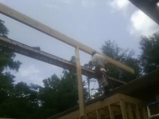 Carpenter setting a ridge beam over a new addition frame — Ice Dam Removal by Roofing Brothers in Votaw