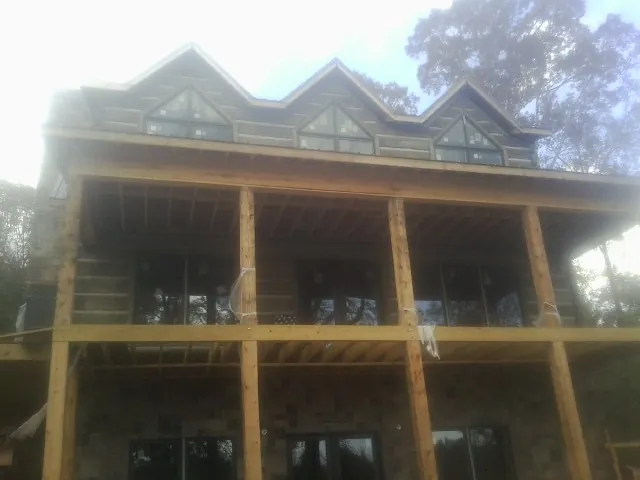 Dormers and porch framing on a large log home under construction — Roof Coating work by our crew in Votaw