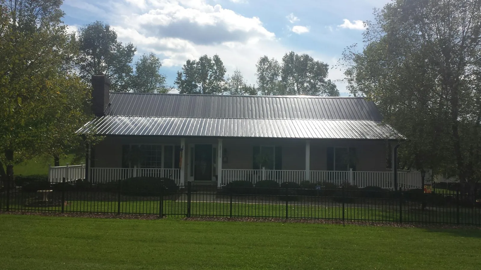 Gray metal roof on a brick ranch with a full width front porch — Gutter Guard Installation work by our crew in Votaw